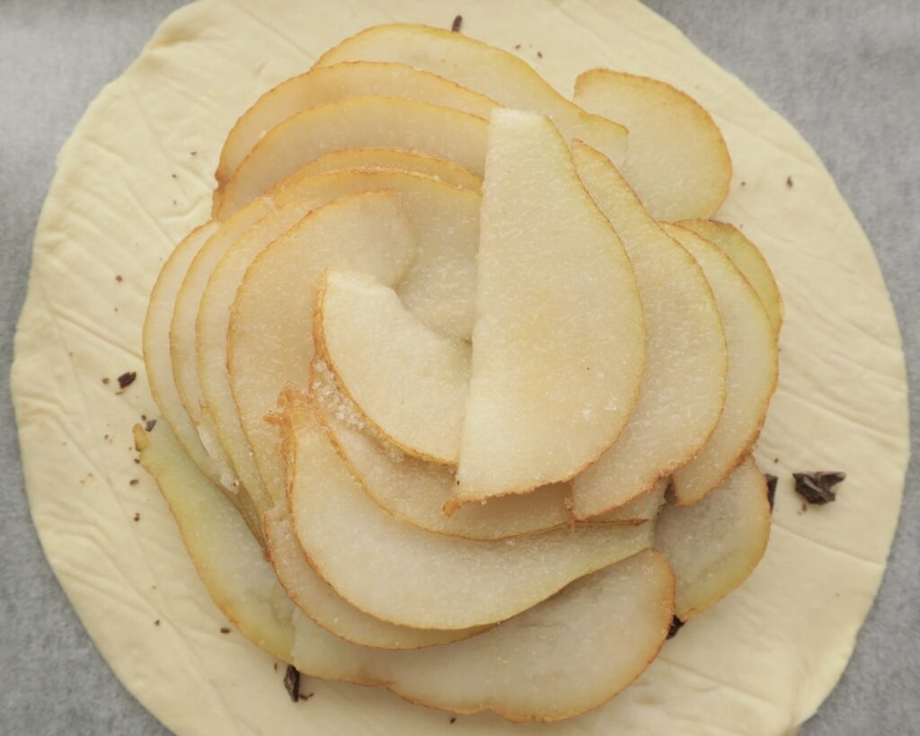 Thinly sliced pears placed on top of raw puff pastry