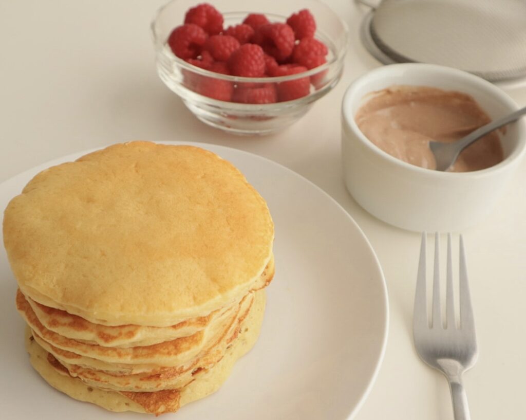 Cottage cheese pancakes in the foreground, pictured with a healthy toppings