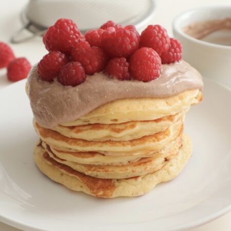 Healthy pancake stack topped with cottage cheese and raspberries