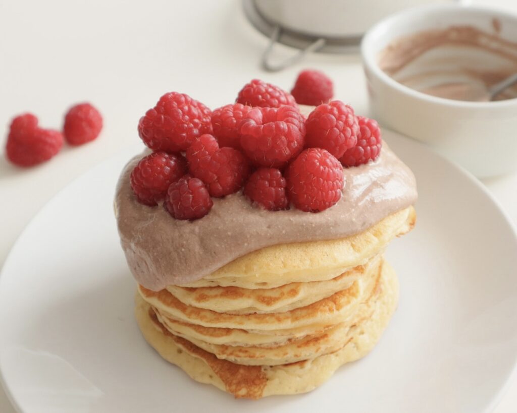 Healthy pancake stack topped with cottage cheese and raspberries