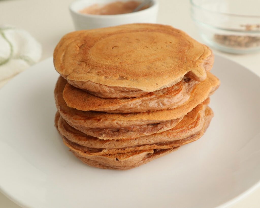 Stack of healthy pancakes with toppings in the background