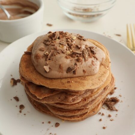 Stack of chocolate-flavored protein pancakes with chocolate toppings