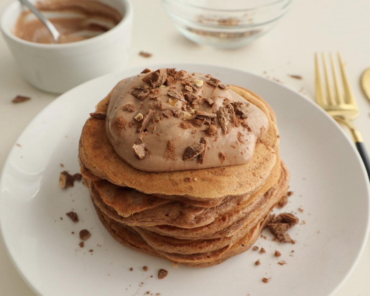 Stack of chocolate-flavored protein pancakes with chocolate toppings